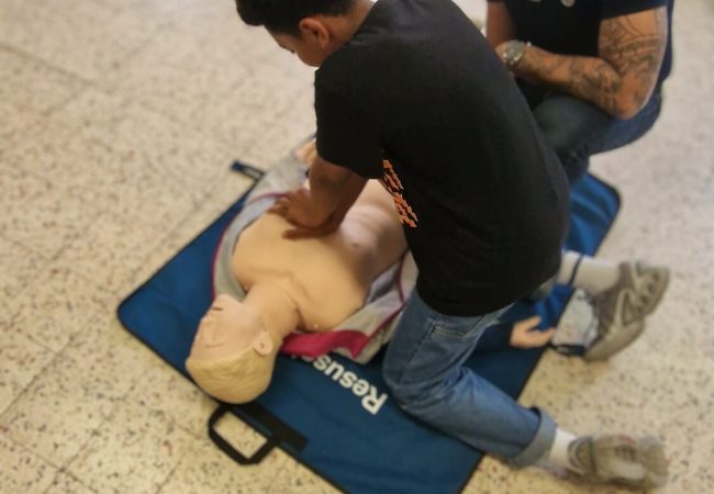 Participant réalisant un massage cardiaque sur mannequin lors d’une initiation aux premiers secours